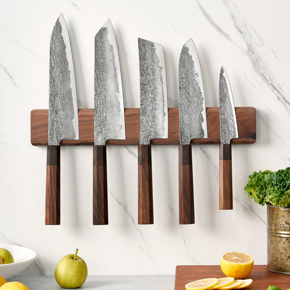 Set of five knives on a magnetic knife holder with a marble countertop background