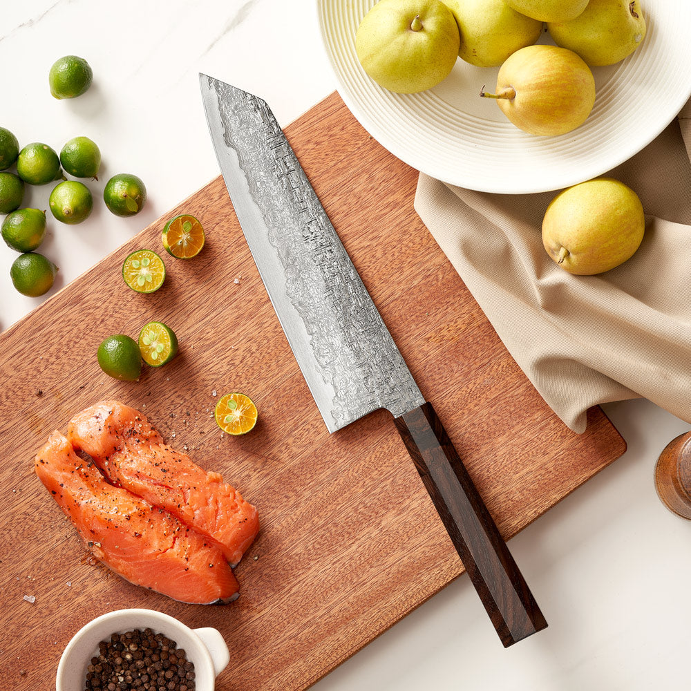 Chef's knife on a wooden cutting board with salmon, limes, and pears.